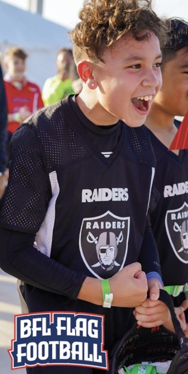 Two young BFL flag football players cheering on the sideline